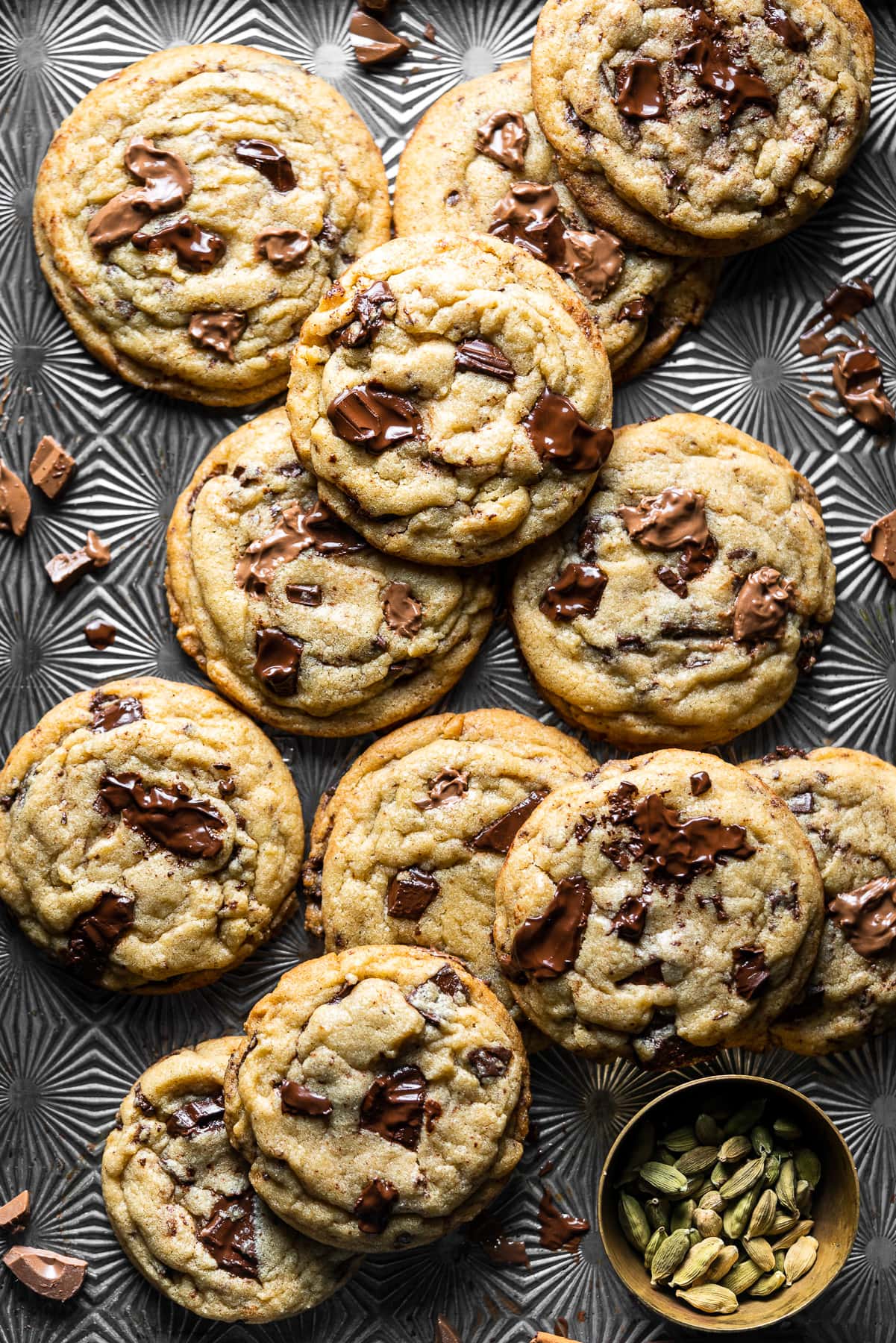 a starburst tray with chocolate chip cookies and a brass bowl with cardamom pods