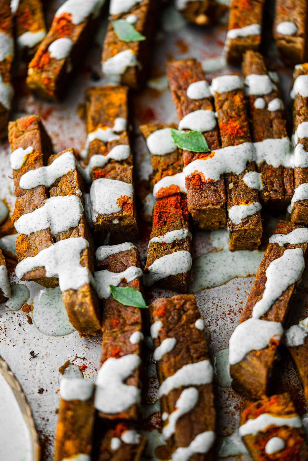 a tray full of chickpea fries drizzled in curry leaf ranch and spices