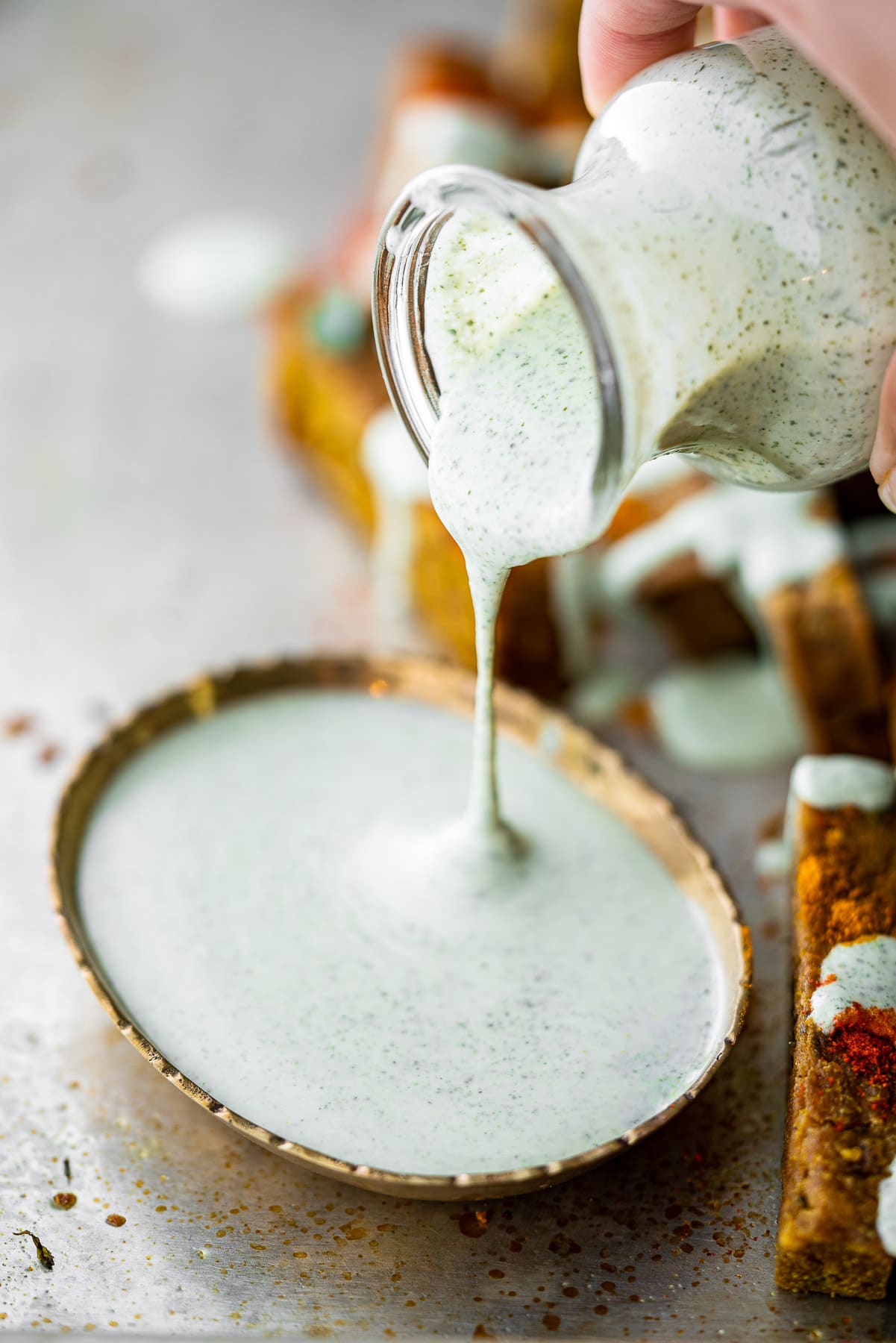 pouring curry leaf ranch for a jar into a bowl for dipping