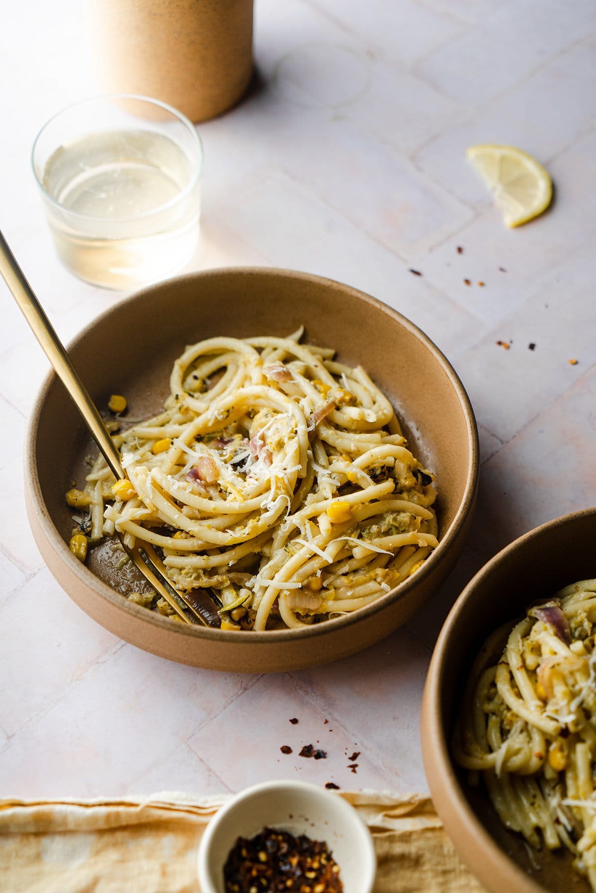 Zucchini Bucatini Pasta in two bowls with red pepper and white wine
