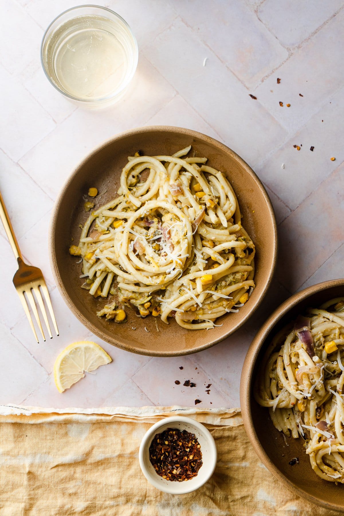 Zucchini Bucatini Pasta in two bowls with red pepper and white wine