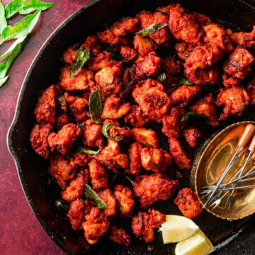 macro shot of chicken 65 in a lodge skillet with curry leaves