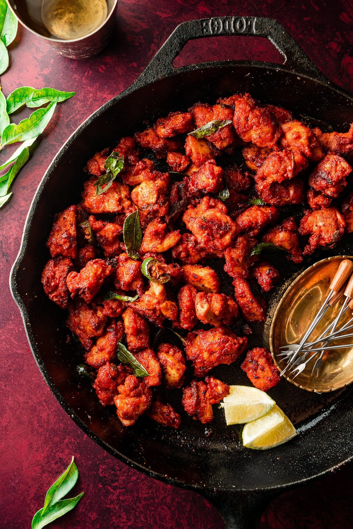 macro shot of chicken 65 in a lodge skillet with curry leaves