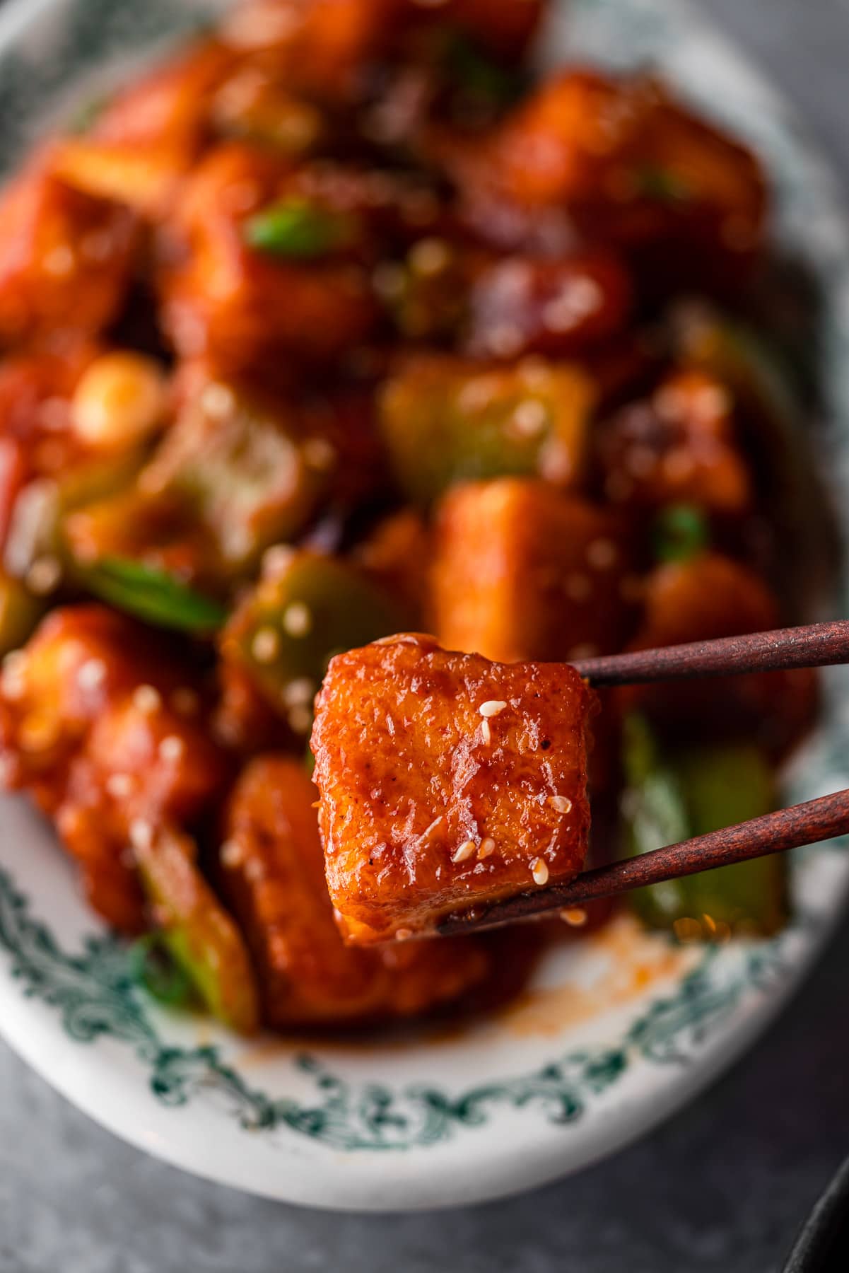 chopsticks holding up a piece of chili paneer