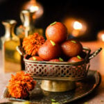 gulab jamuns in a raised platter with marigolds