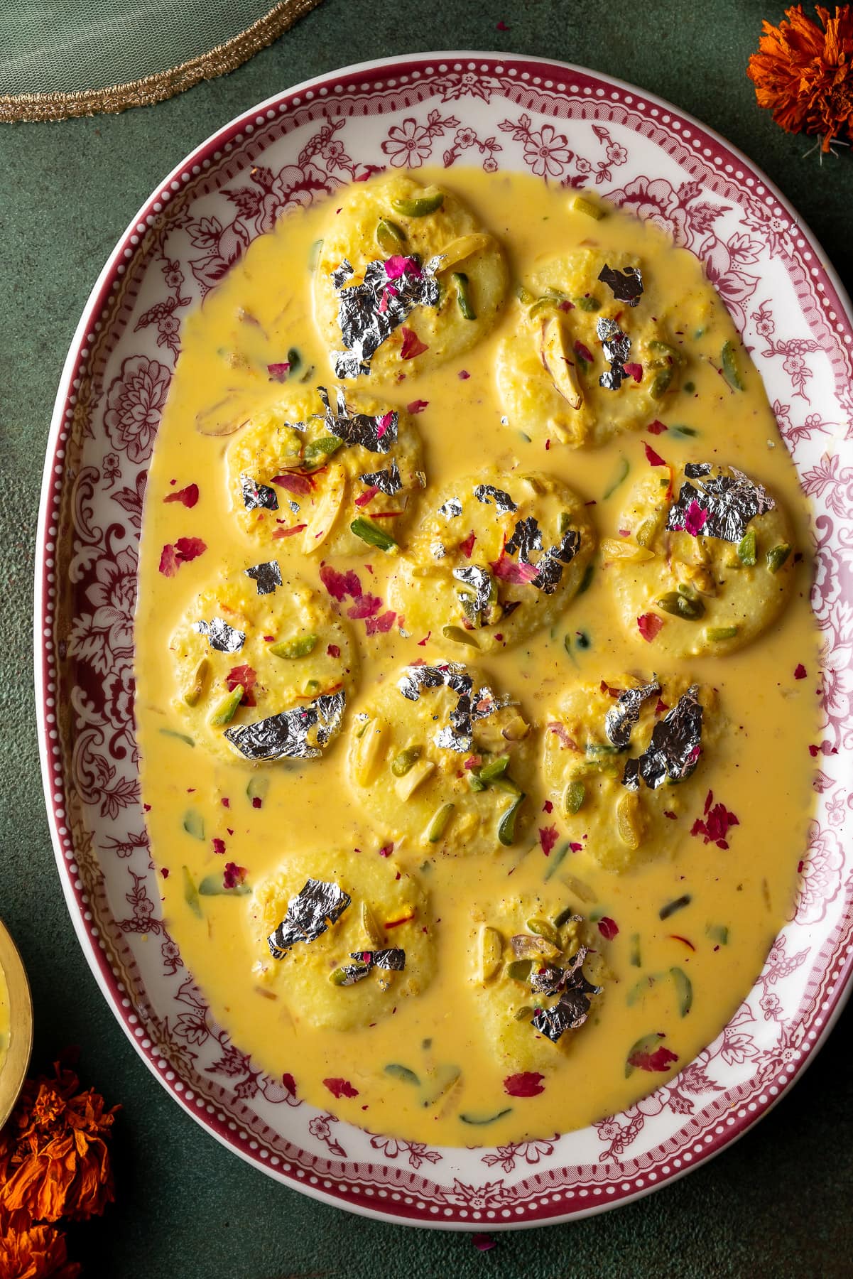 platter full of ras malai with pistachios and flowers