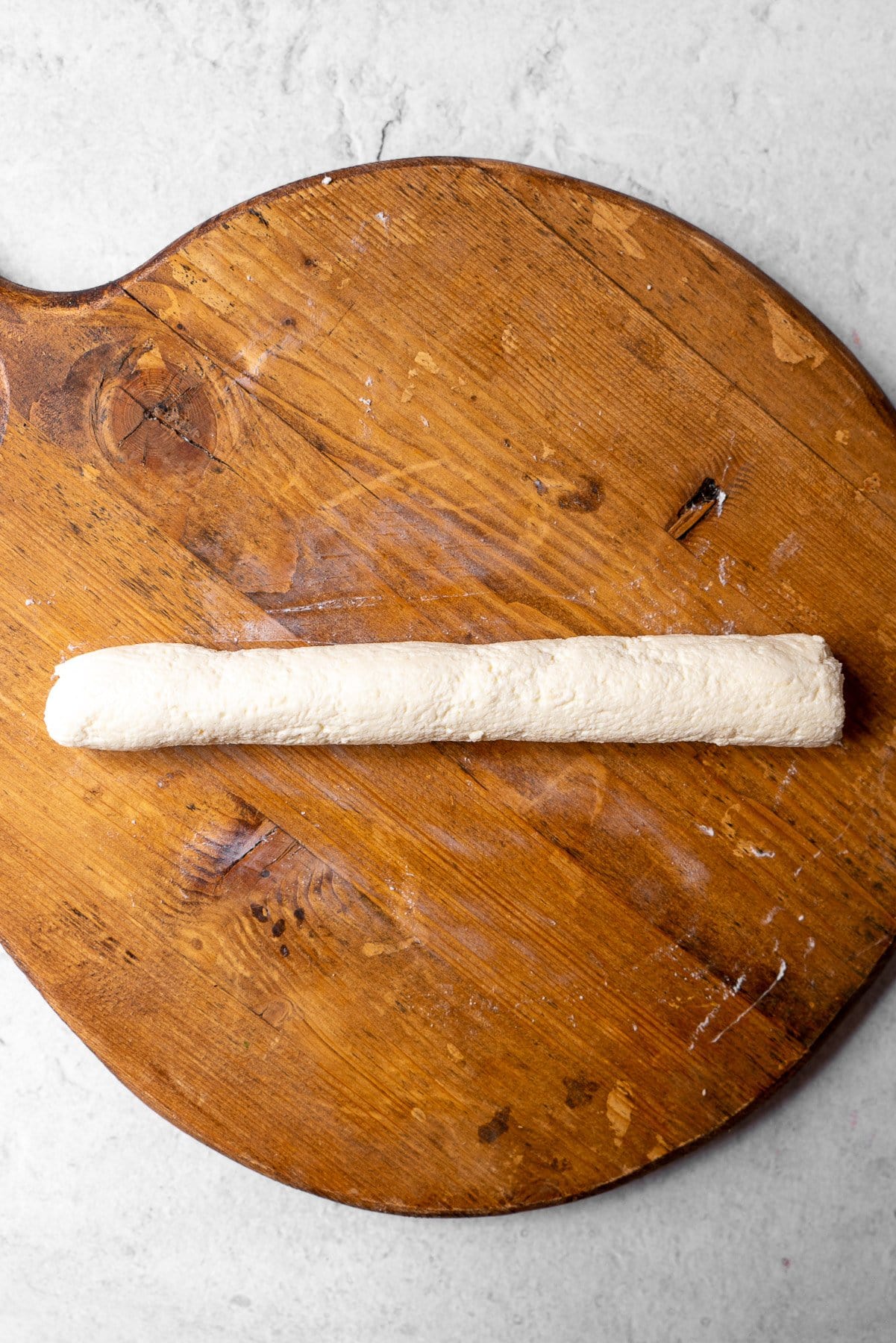 a log of paneer rolled out on a wooden board