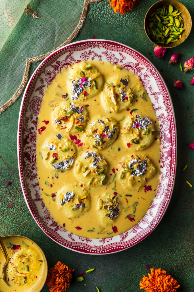 platter full of ras malai with pistachios and flowers