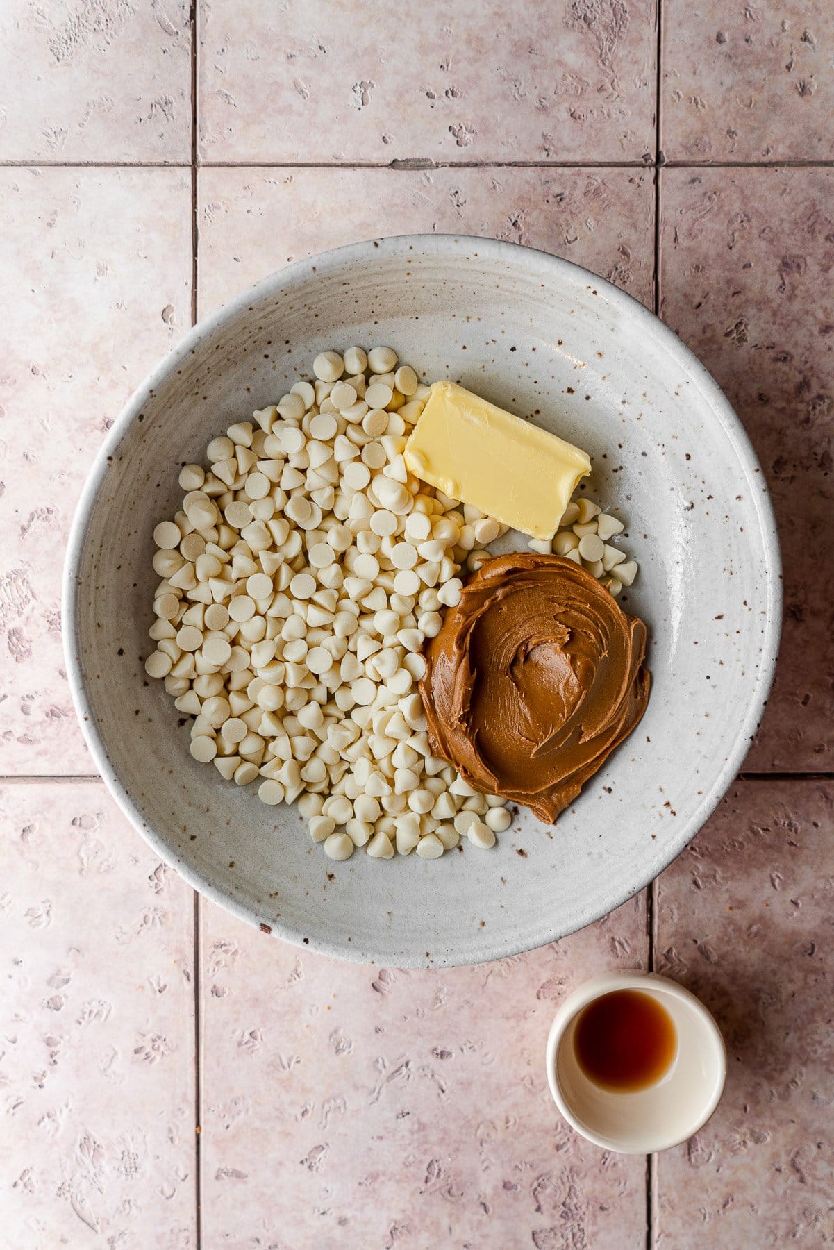 bowl with white chocolate chips, butter, cookie butter and another small bowl with vanilla extract