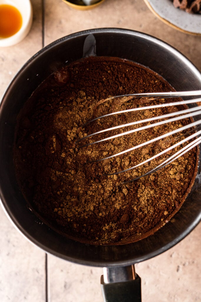 whisking chai hot chocolate ingredients in a sauce pan