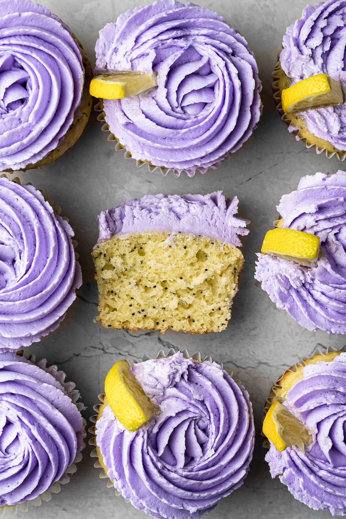 Tops of Lemon Poppyseed Cupcakes in a row with the middle cupcake cut in half