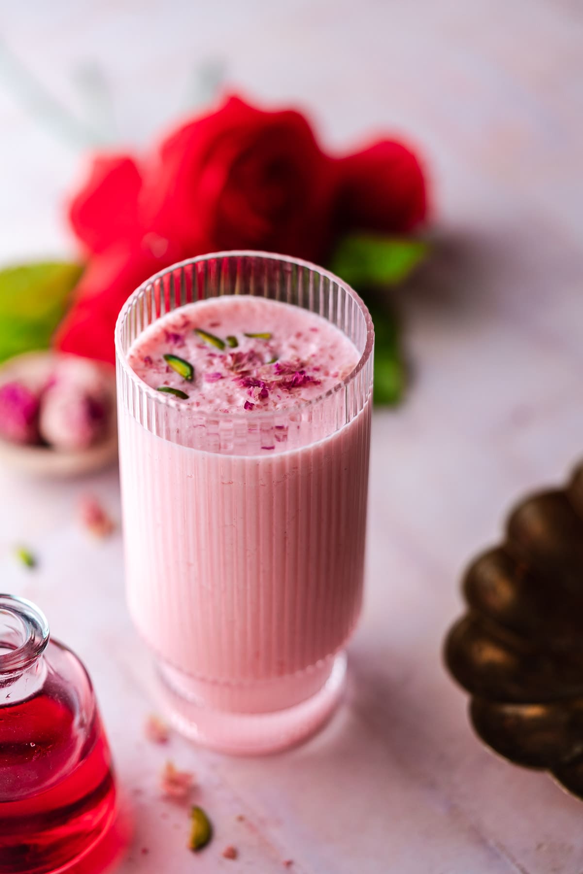 glass of rose lassi with roses in the background