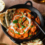 butter chicken in a bowl with garlic naan