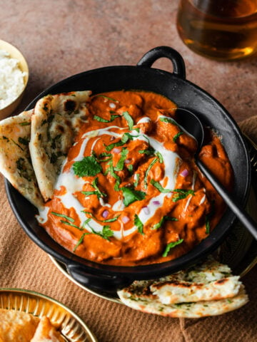 butter chicken in a bowl with garlic naan
