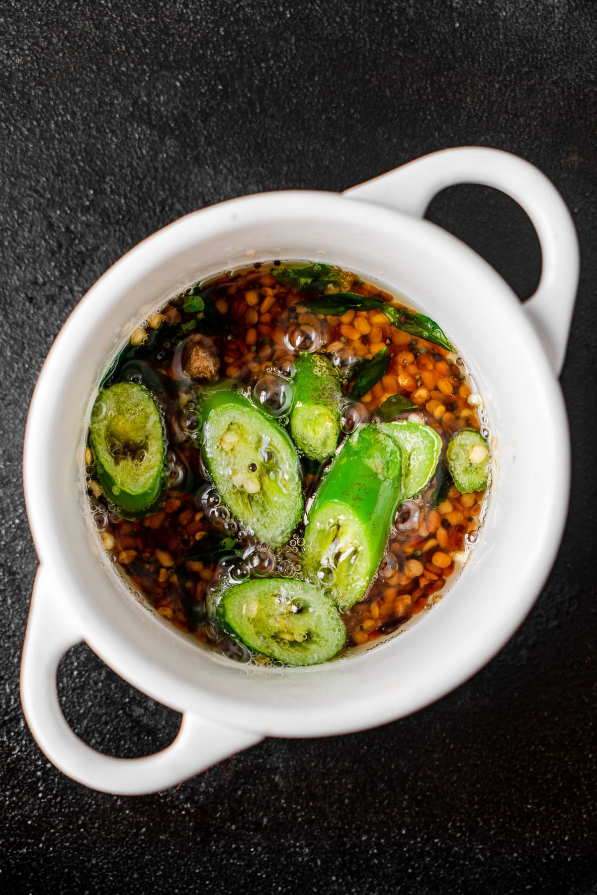 cocotte with urad dal, curry leaves, and chilis in an oil tempering