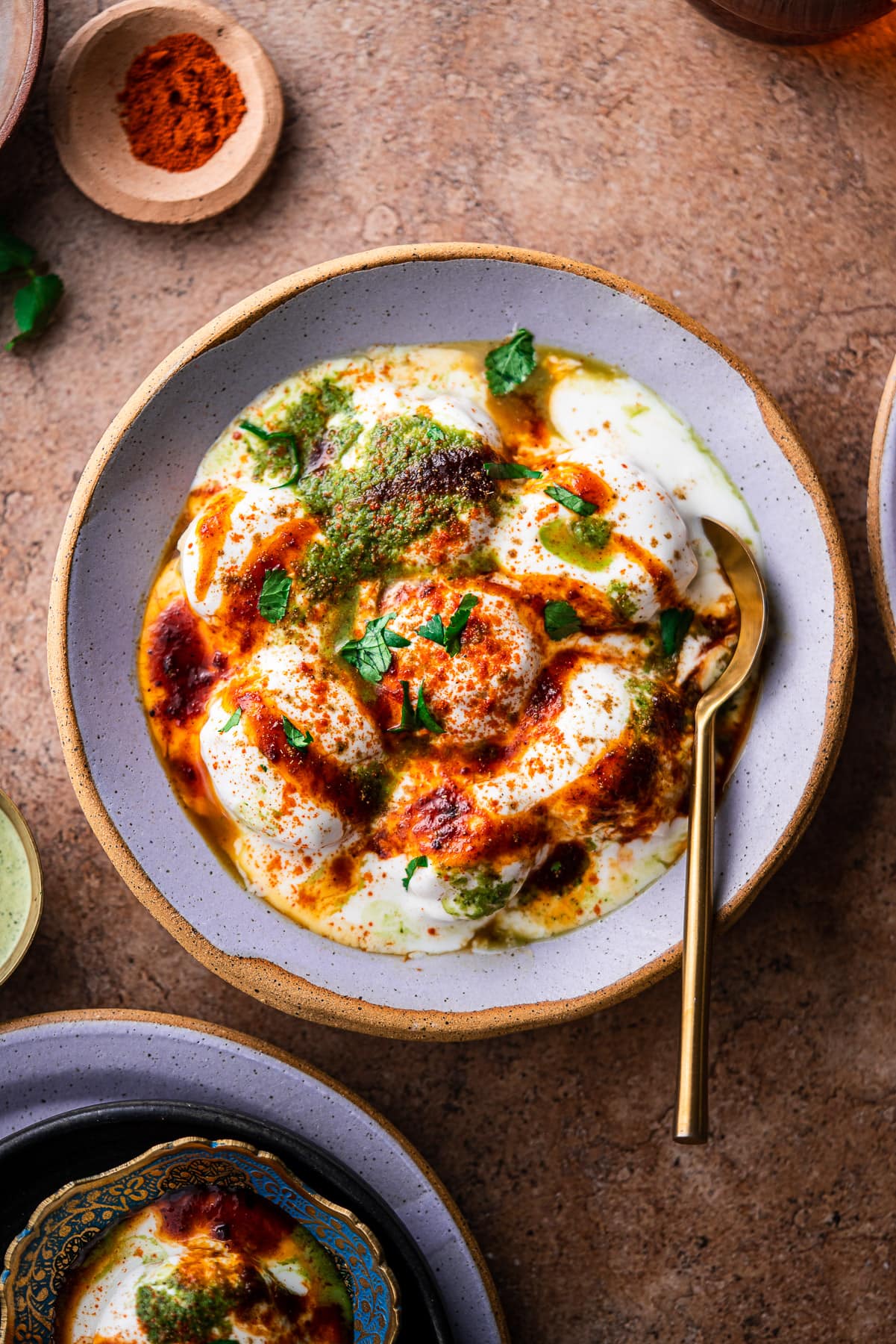 a serving bowl with dahi bhallas and chutney