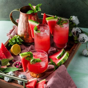 serving tray with watermelon rose coolers, pitcher, florals, and fresh fruit and mint