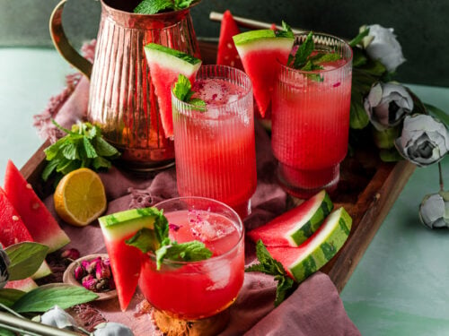 serving tray with watermelon rose coolers, pitcher, florals, and fresh fruit and mint