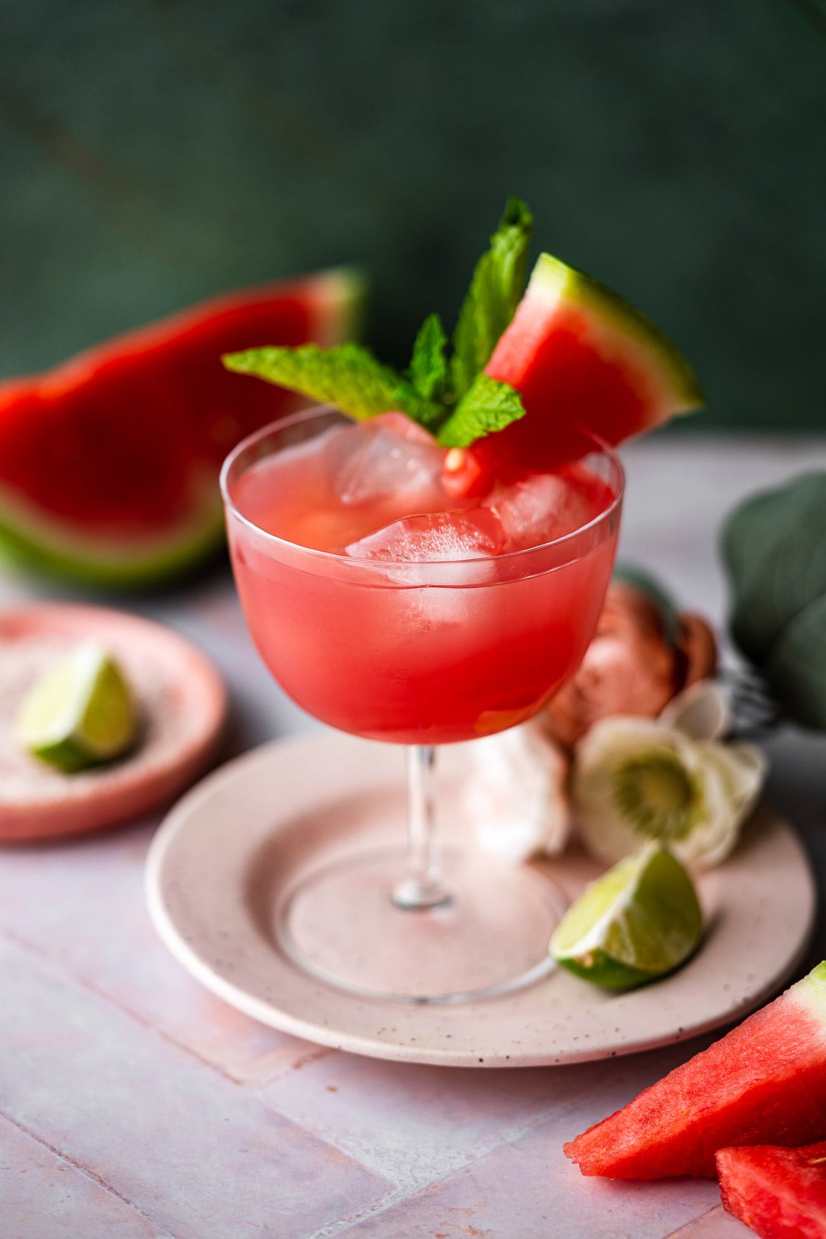 fresh homemade watermelon juice in a coupe with lime, fresh watermelon, and mint