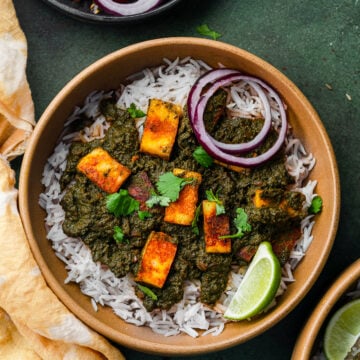 a bowl of swiss chard saag paneer with tomato onion salad