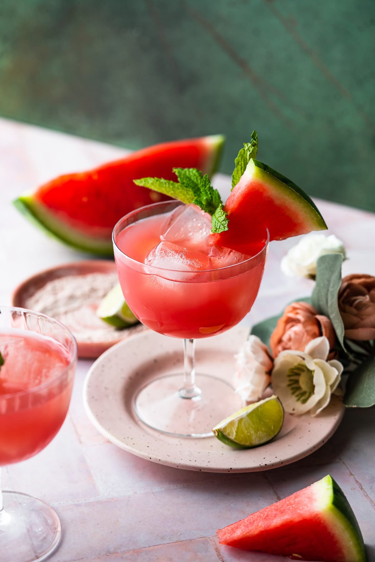 fresh homemade watermelon juice in a coupe with lime, fresh watermelon, and mint