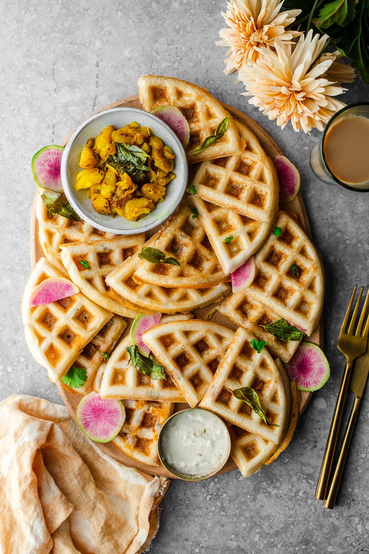 platter with quarters of dosa waffles with a bowl of aloo sabzi and a bowl of coconut chutney.