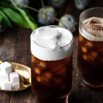 two glasses of coffee with cold foam on top of one.