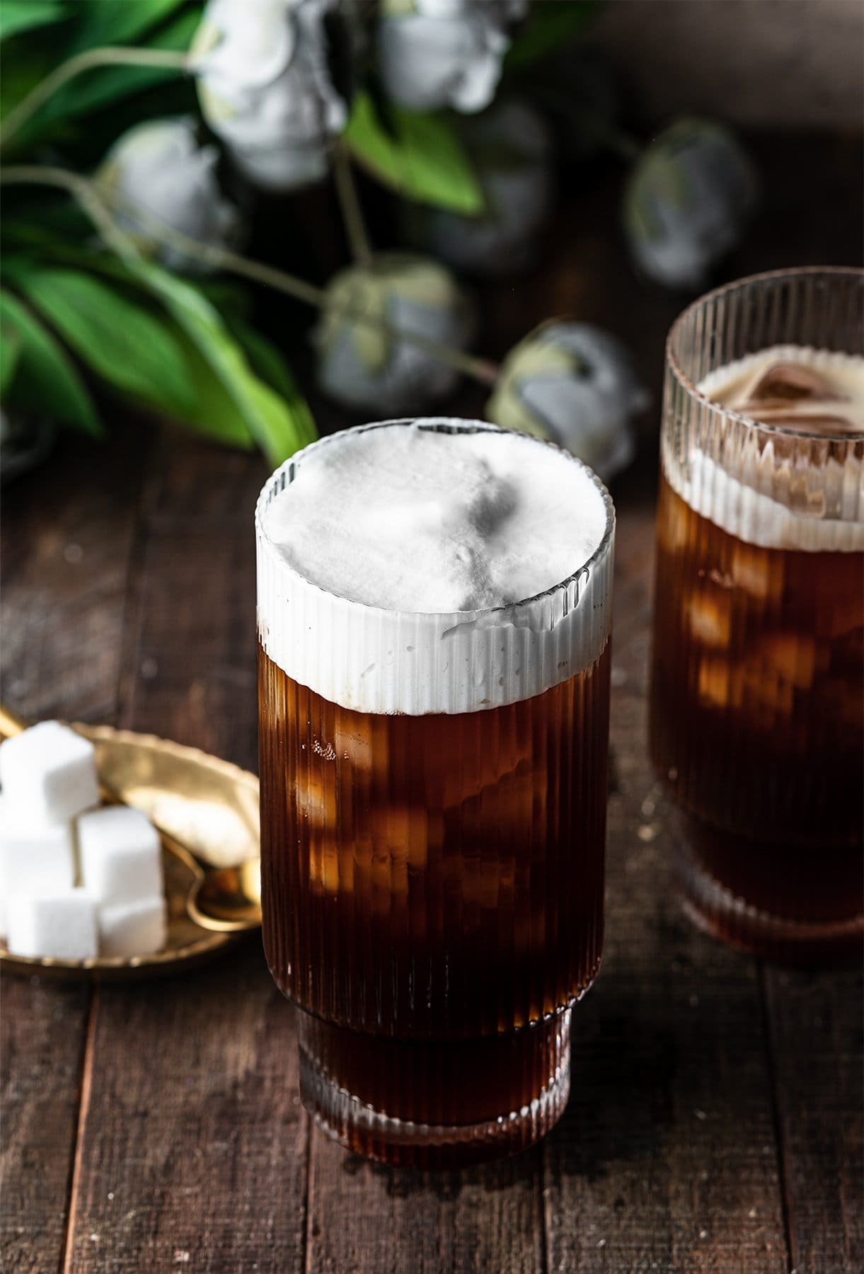 two glasses of coffee with cold foam on top of one.