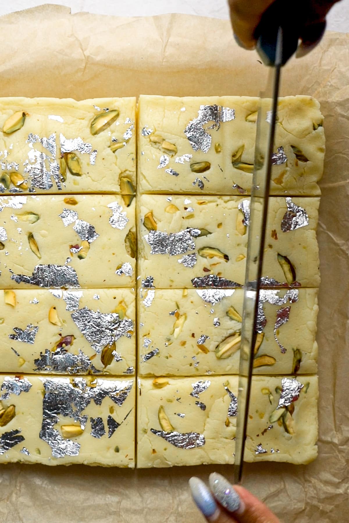 Cutting Decorate Milk Barfi with a long knife.