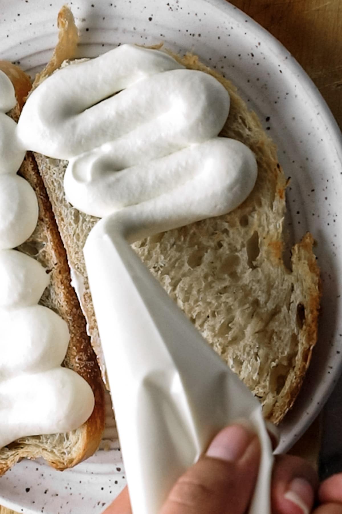 Piping whipped ricotta toast with a piping bag.