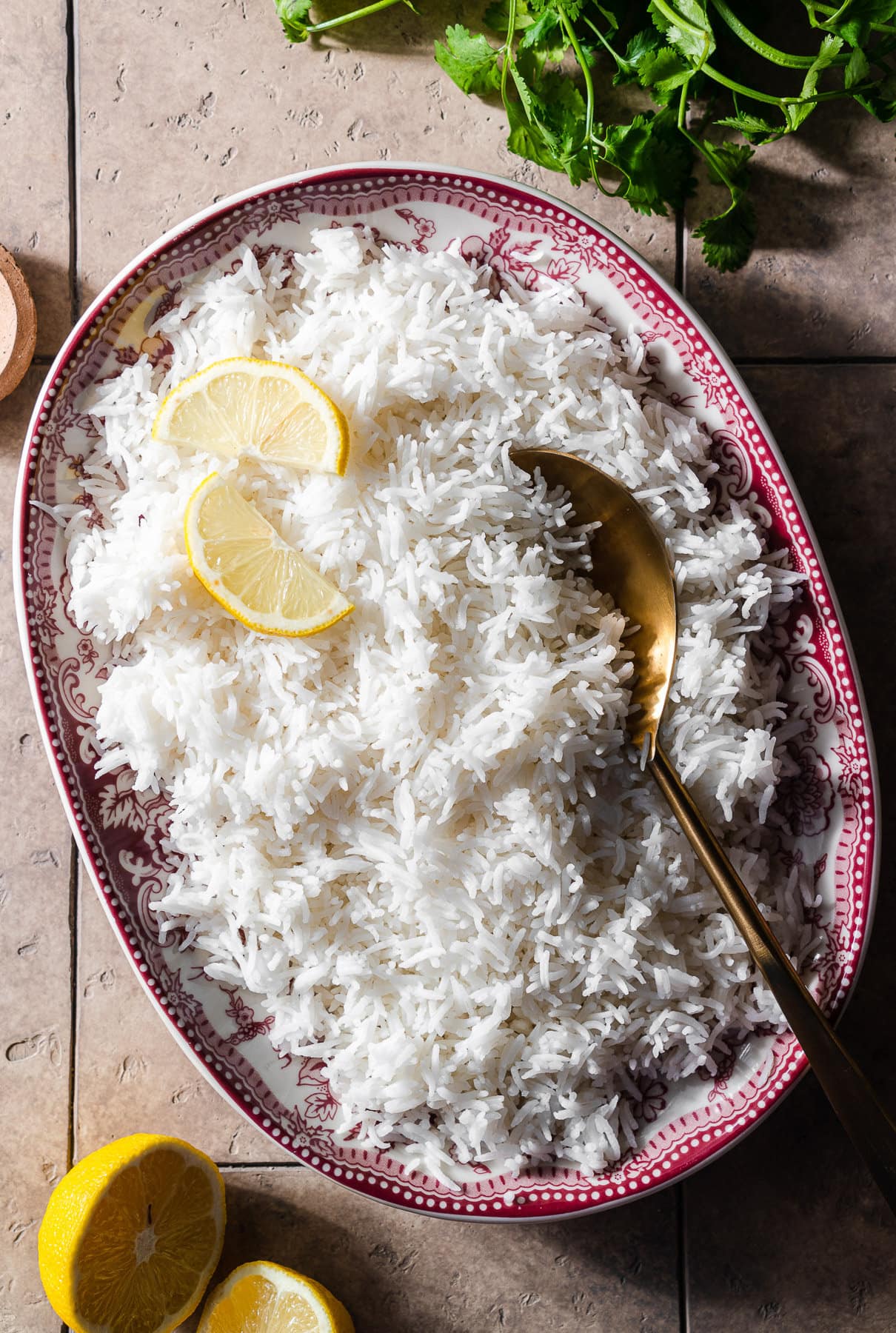 basmati rice in a platter with lemon slices and a gold spoon.