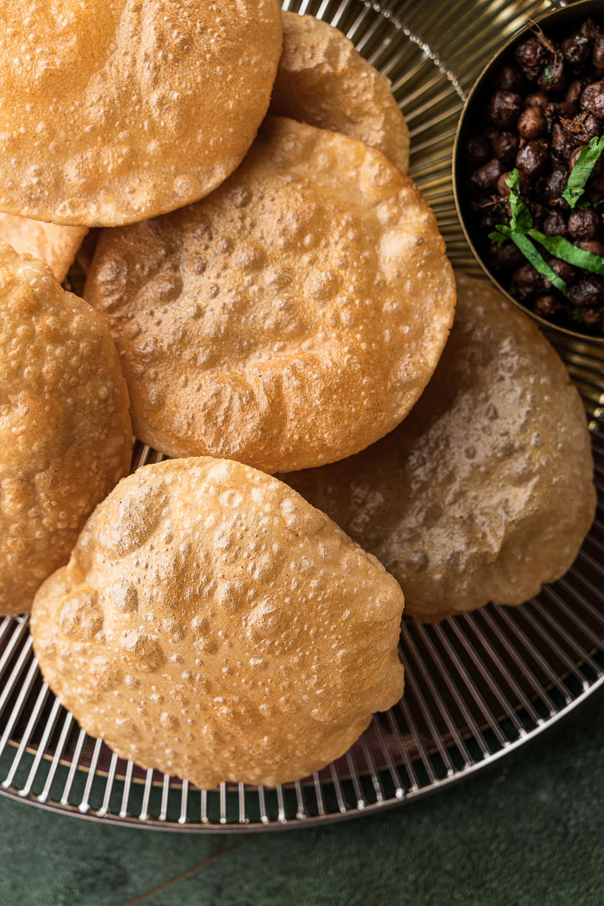 Pile of puris on a serving platter with a side of kala chana.