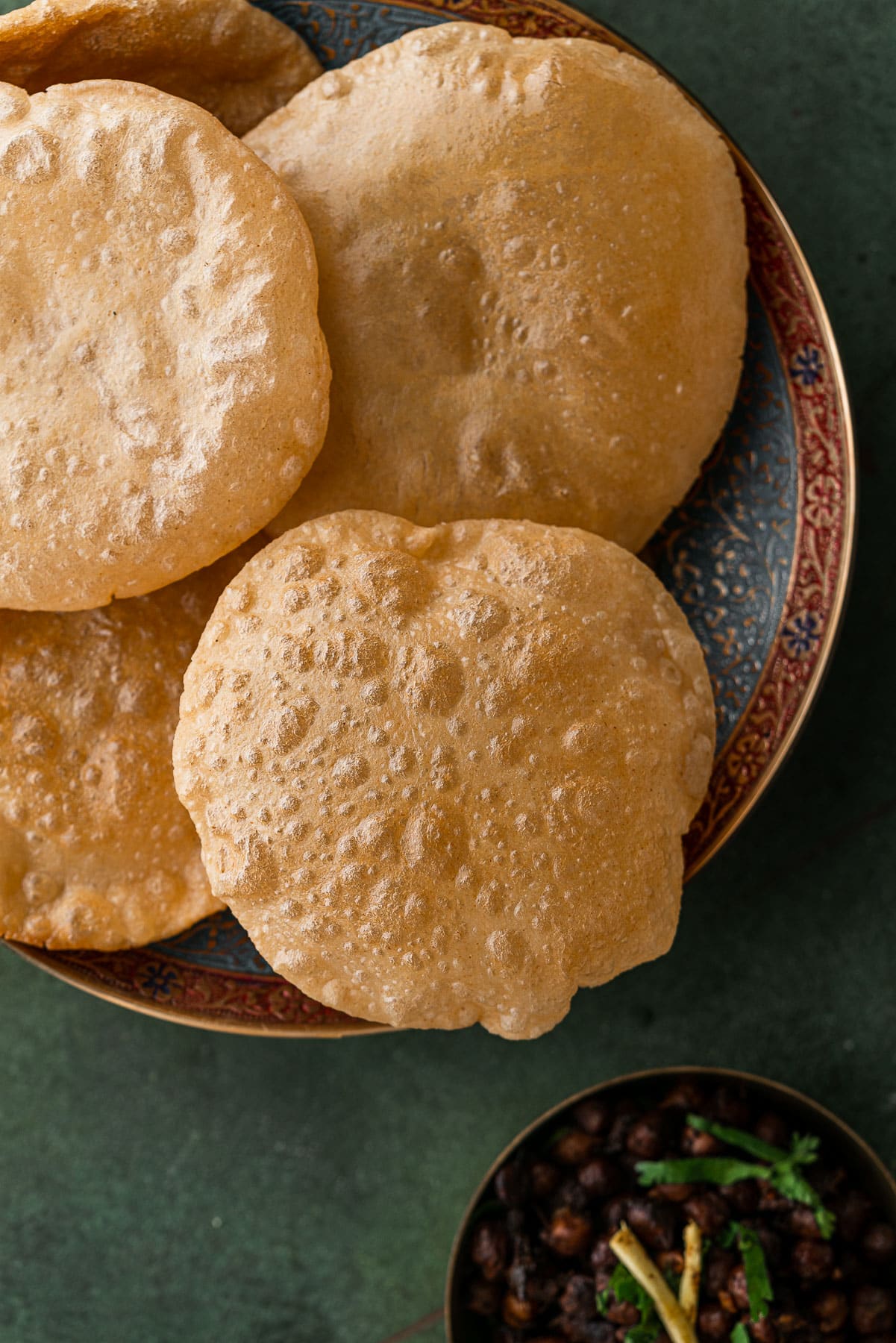 Puffy puris in a decorative bowl with a side of kala chana.