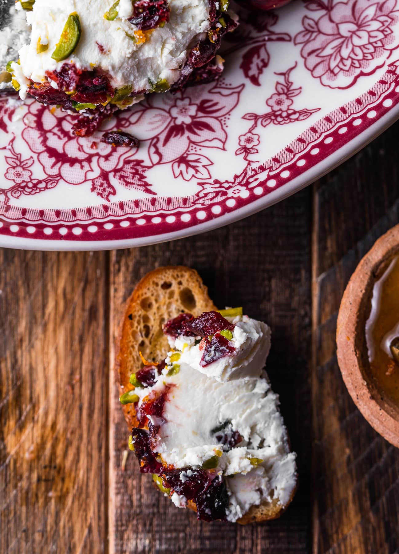 A crostini with a schmear of cranberry pistachio goat cheese log.