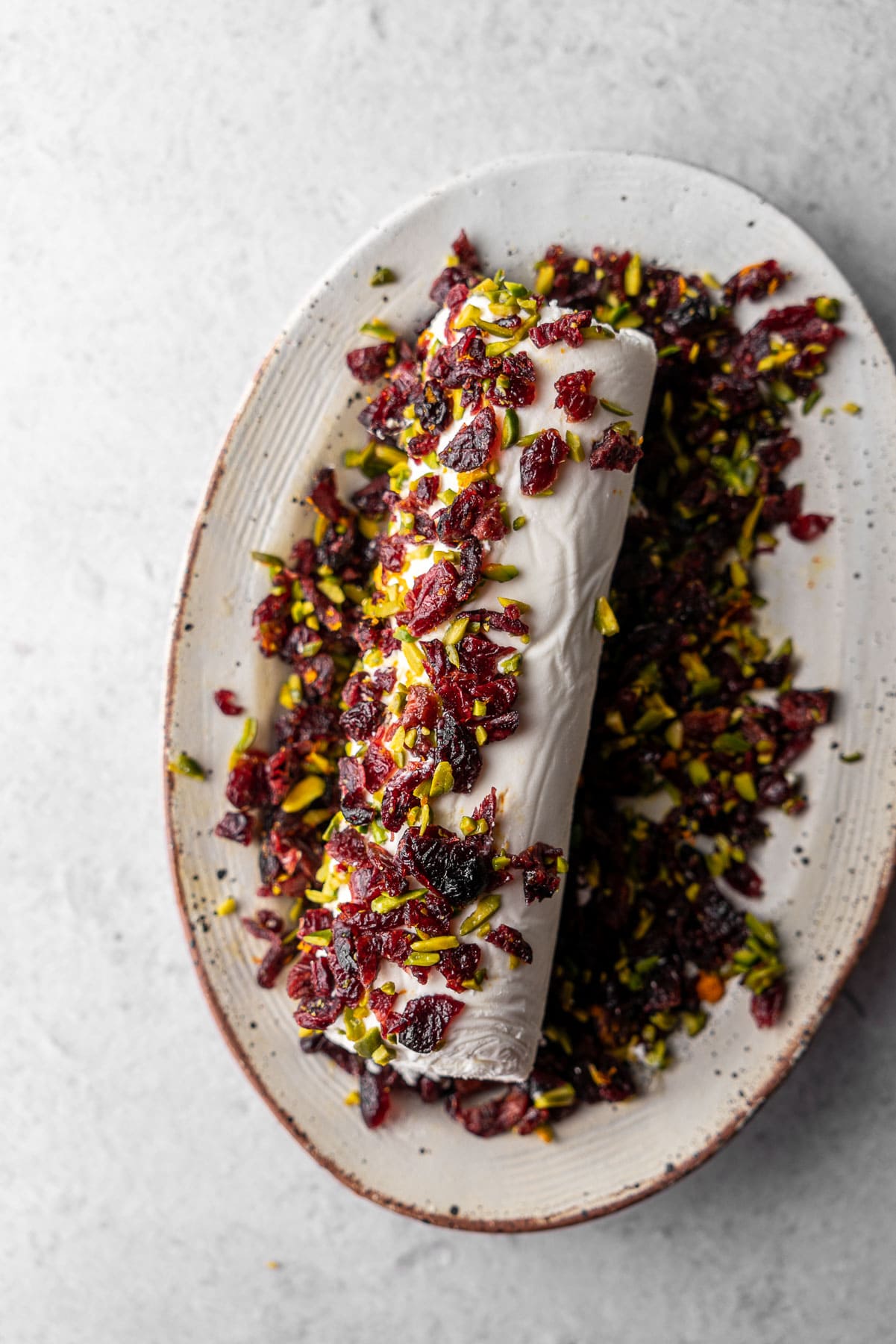 A goat cheese log half rolled in chopped cranberries and pistachios.