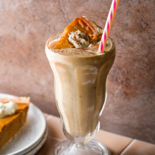A pumpkin pie milkshake with a slice of pie and a straw.