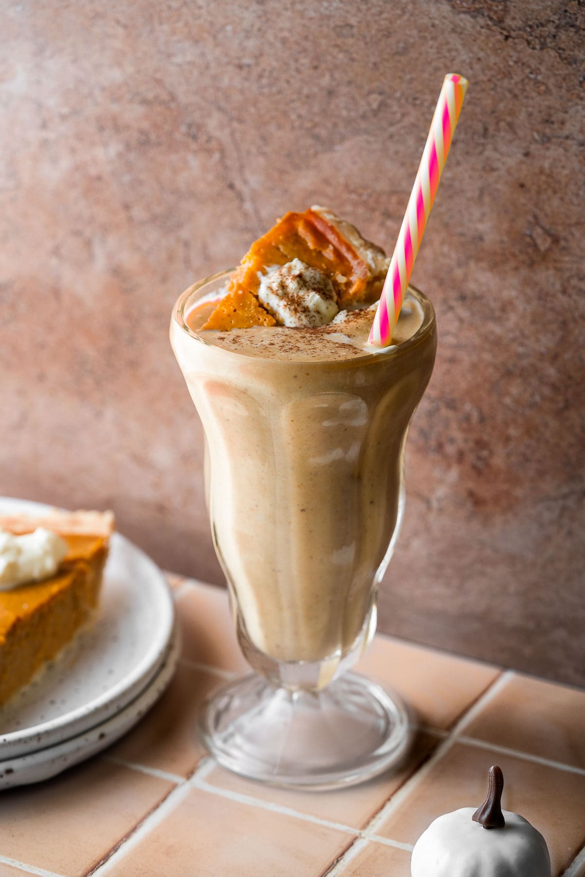 A pumpkin pie milkshake with a slice of pie and a straw.