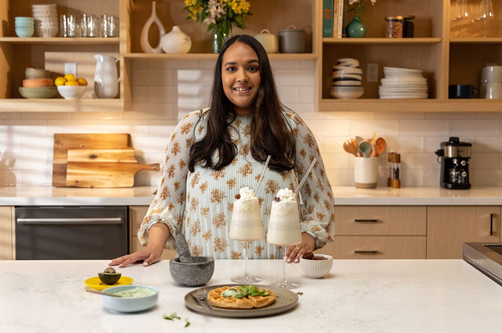 Shweta Garg in a kitchen with milkshakes and a waffle.
