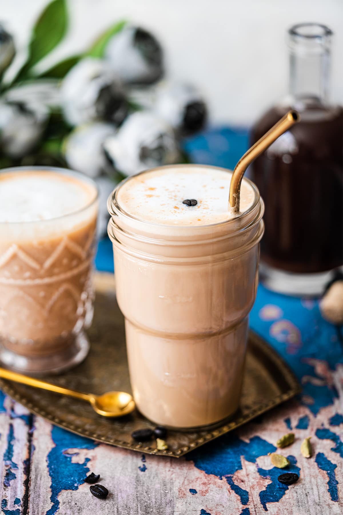 Two cups of dirty chai in a platter with a gold straw and spoon.