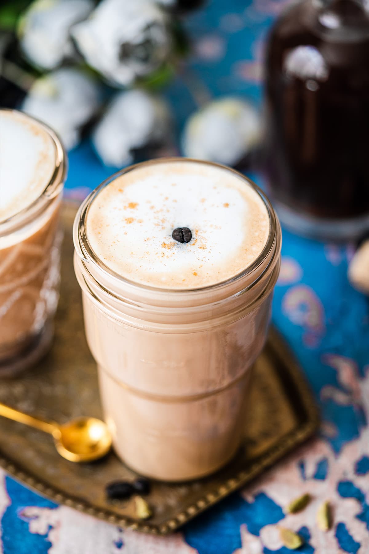 Two cups of dirty chai in a platter with a gold straw and spoon.