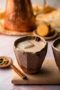 A cup or chai horchata in a ceramic cup with cinnamon on a wooden board.