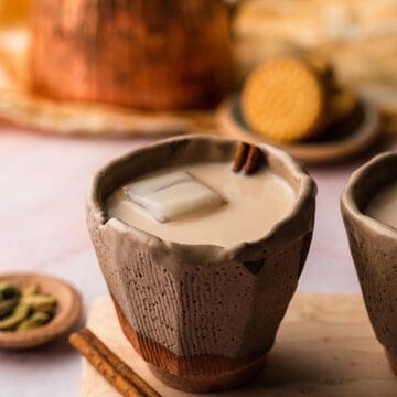 A cup or chai horchata in a ceramic cup with cinnamon on a wooden board.