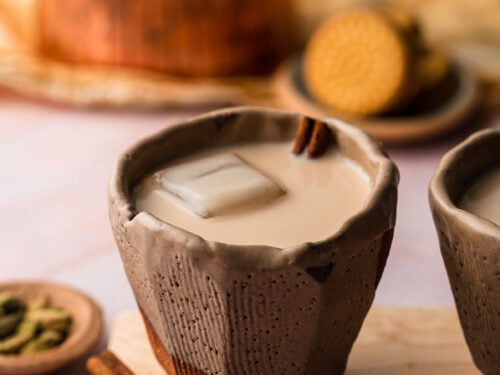 A cup or chai horchata in a ceramic cup with cinnamon on a wooden board.