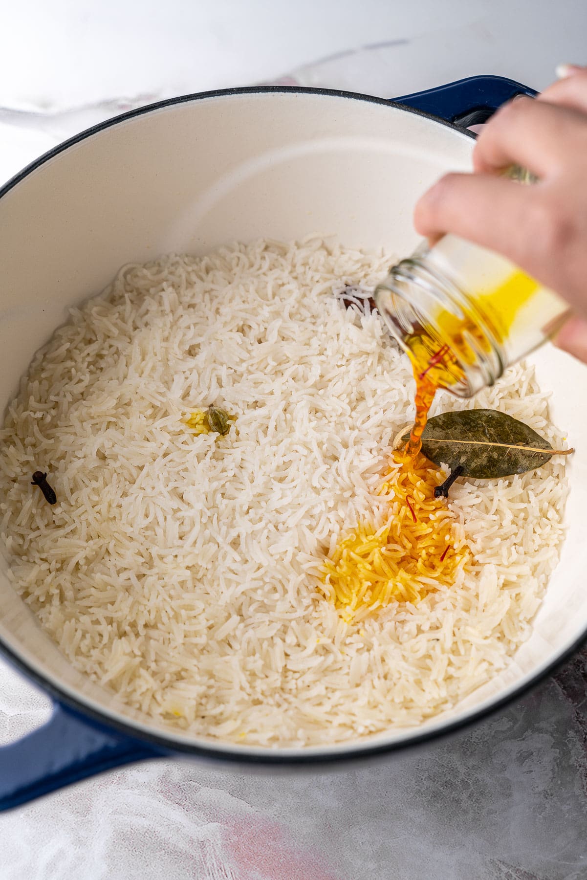 Pouring bloomed saffron water over a pot of basmati rice.