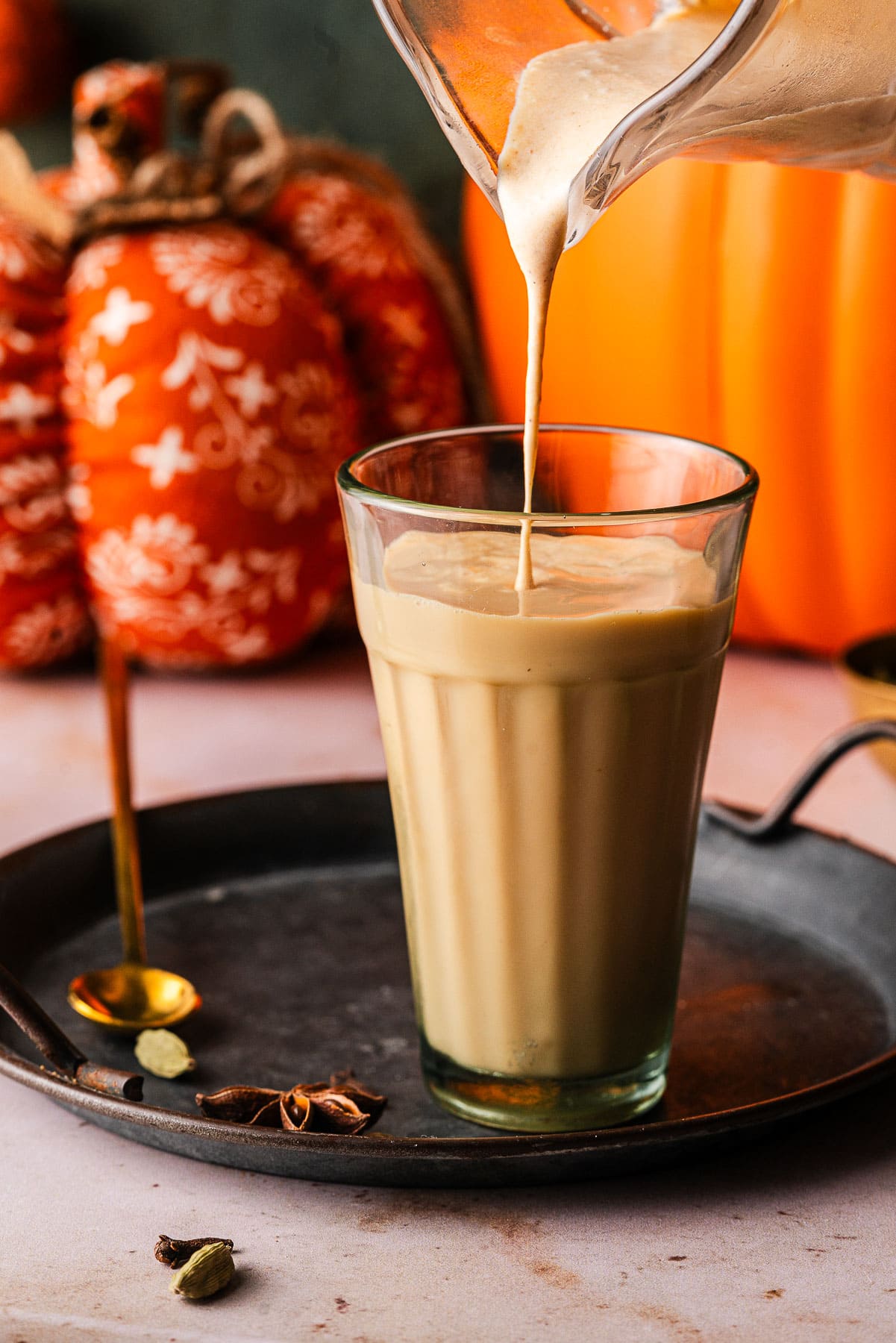A Chai Latte on a platter with Pumpkin Cream being poured on top.