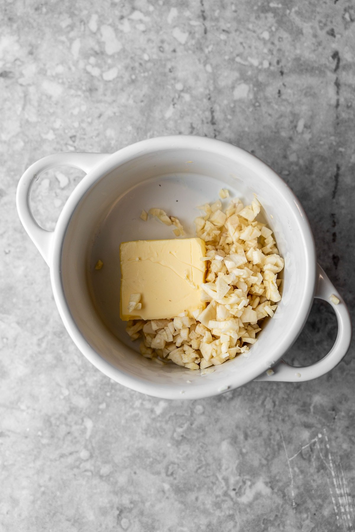 Minced Garlic with a slab of butter in a mini cocotte.