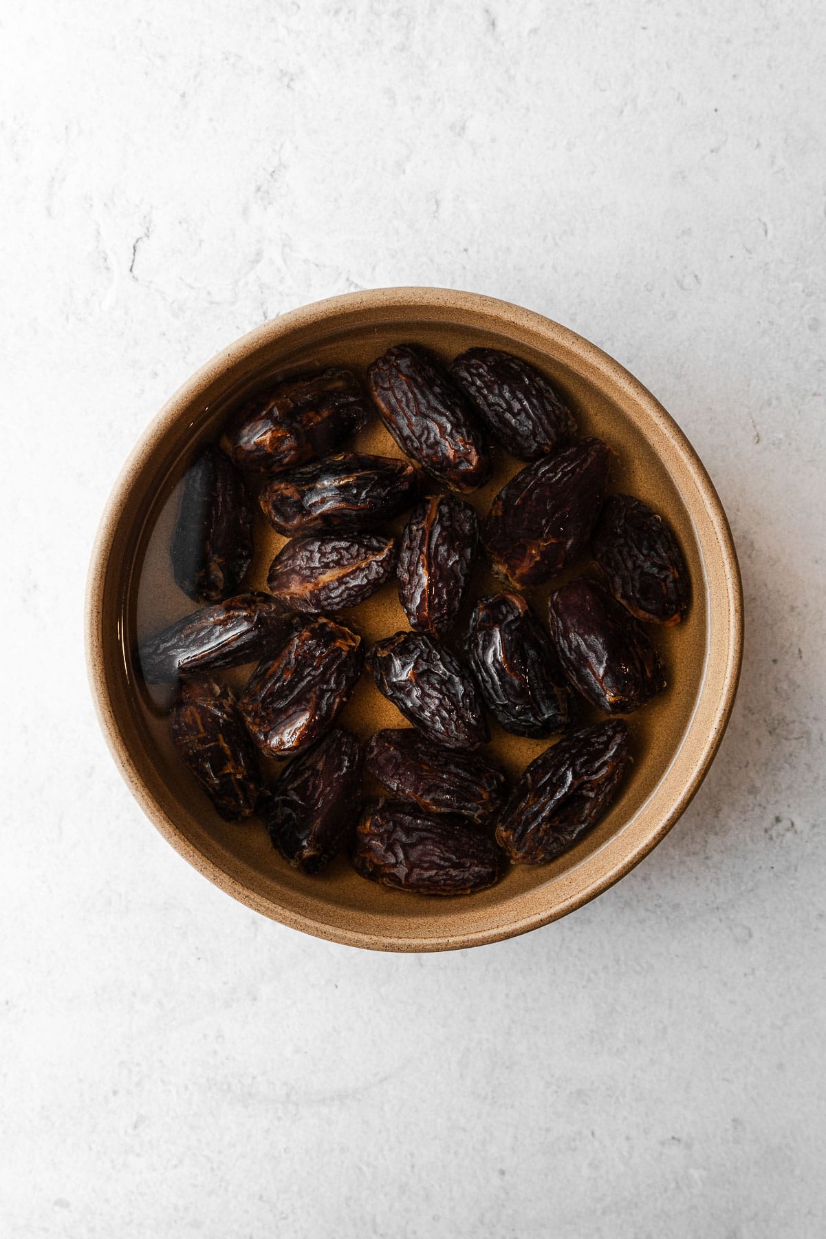 A bowl filled with fresh dates soaked in water.