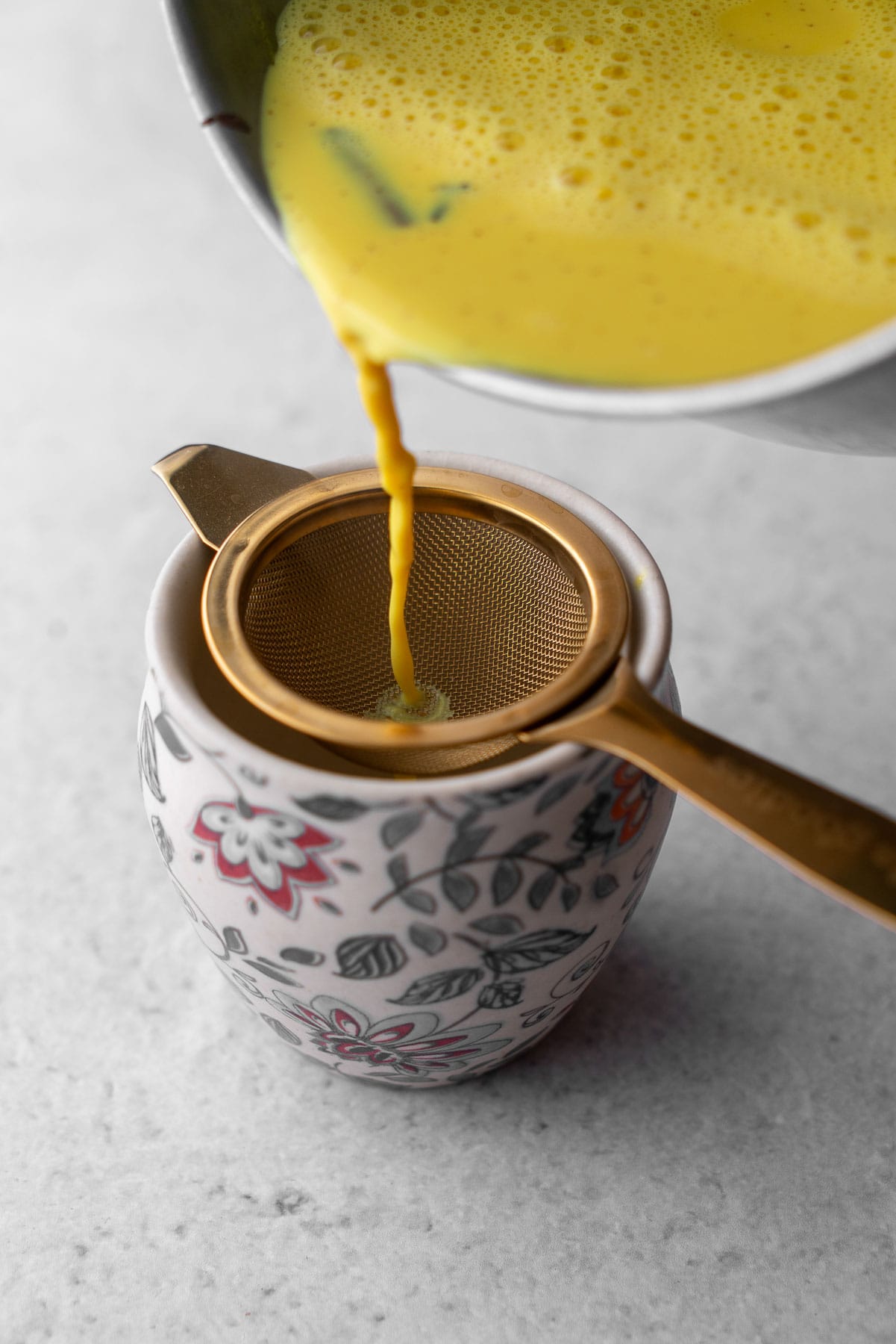 Haldi doodh pour over a strainer into a kulhad.