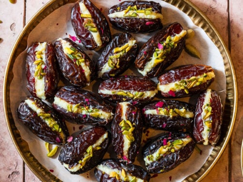 A plate full of cream stuffed dates with a diya and saffron.