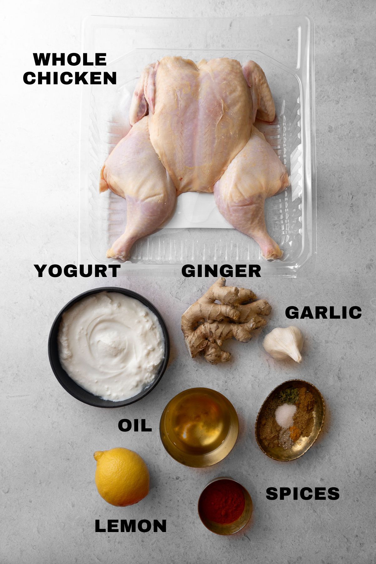 Spatchcocked chicken, yogurt, ginger, garlic, spices, oil, and lemon ingredients with labels.